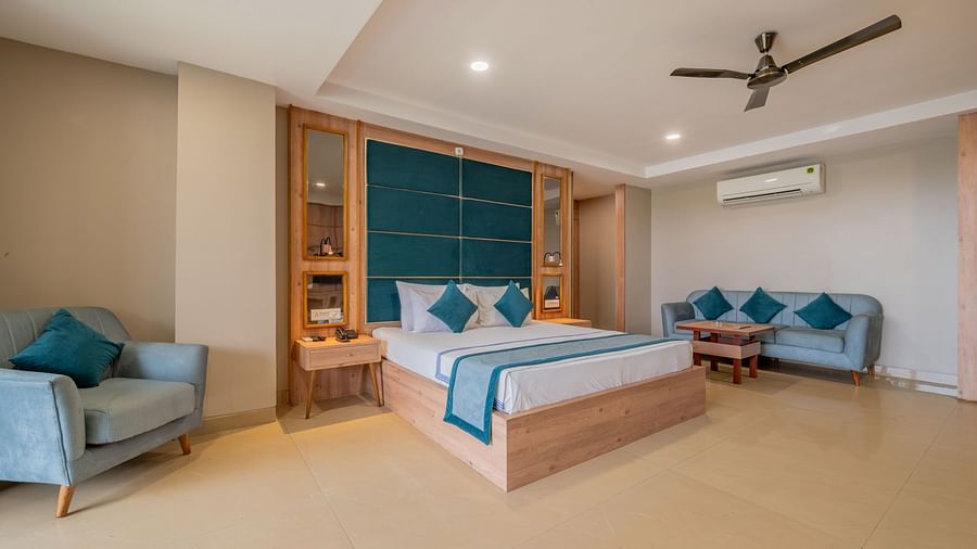 A spacious guest room at Hotel Highway King Shahpura featuring a comfortable bed and a sofa seating area.