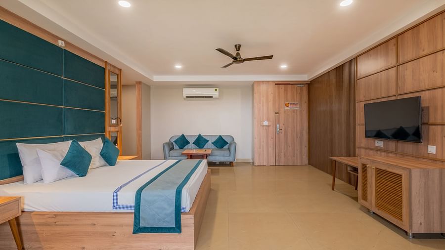 Another view of a guest room at Hotel Highway King Shahpura with a large bed and a TV unit.