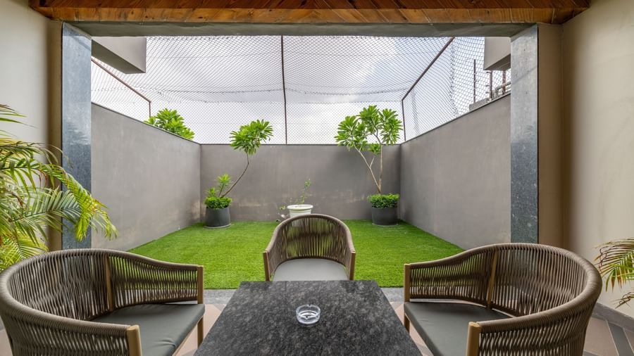 A private outdoor patio with seating and artificial grass, accessible from a room at Hotel Highway King Shahpura.