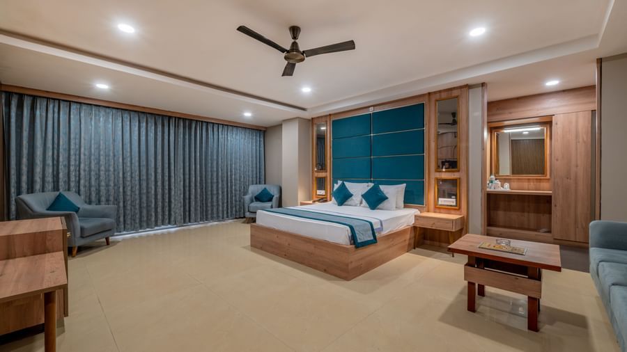 A wide angle view of a modern guest room at Hotel Highway King Shahpura, showing the bed and lounge area.