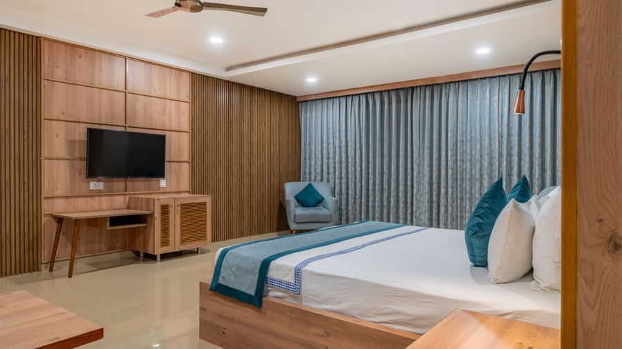 A well-appointed guest room with a bed, TV, and wooden furnishings at Hotel Highway King Shahpura.