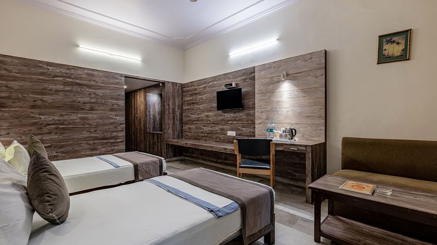 Another perspective of a well-furnished guest room with two beds and a sitting area at Hotel Highway King Shahpura