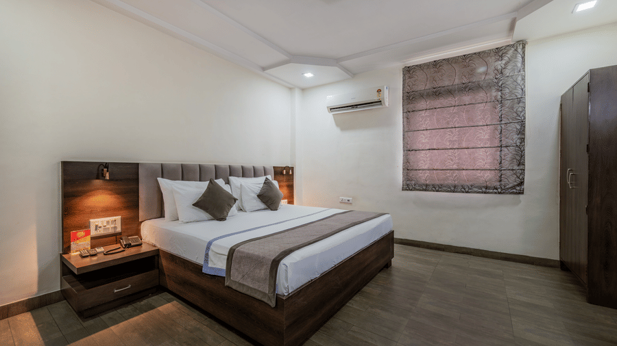 King Standard Room with a dark wooden headboard, air conditioning, and a wooden wardrobe at Hotel Highway King, Shahpura, comfortable.