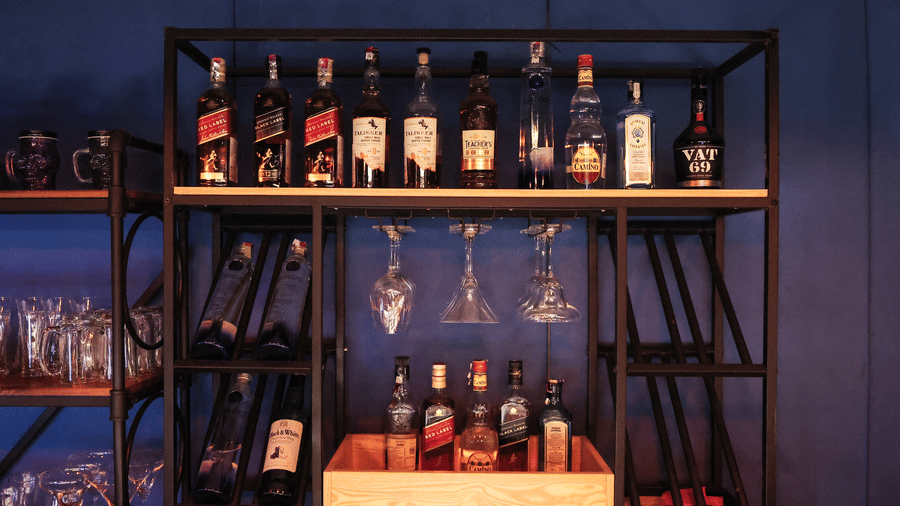 Close-up of the industrial-style black metal bar shelving with bottles of wine, spirits, and hanging glassware at Hotel Hukam's Lalit Mahal.