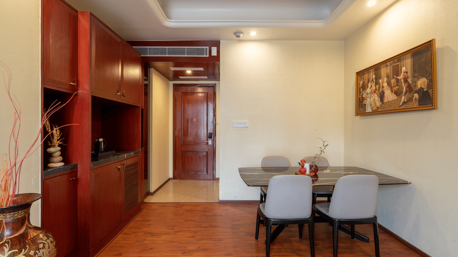 Apartment-style dining area with a small table, chairs, wooden flooring, and a built-in cabinet or kitchenette at Hotel Hukam's Lalit Mahal.
