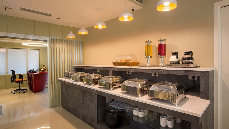 A bright restaurant buffet area with food warmers, juice dispensers and a reception desk in the background - Hotel Langford Keys by TGI, Shanti Nagar
