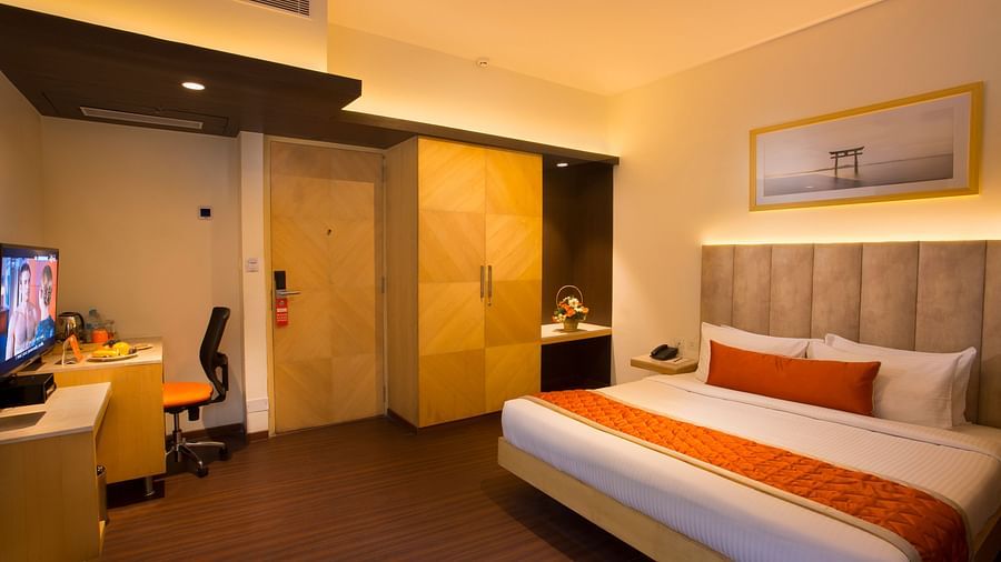 A spacious hotel room with a comfortable bed, ambient lighting and a television, featuring a wooden wardrobe and desk - Hotel Langford Keys by TGI, Shanti Nagar