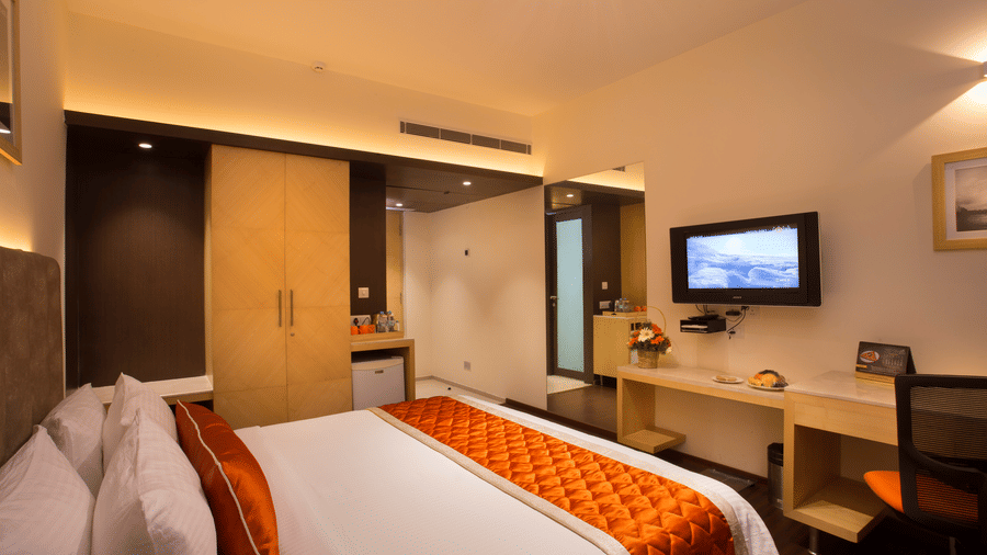 The Executive Room at Hotel Langford Keys by TGI with a double bed, wall-mounted television opposite the bed, a writing desk with chair, and a wardrobe near the entrance.