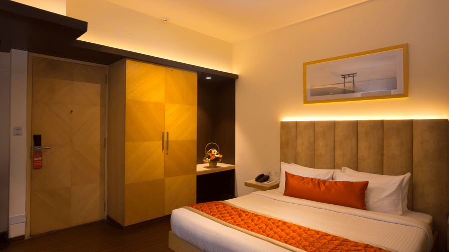 A well-appointed Executive Room at Hotel Langford Keys by TGI with a double bed featuring a padded headboard, bedside tables with lamps, wall-mounted artwork, and a wardrobe with sliding panels.