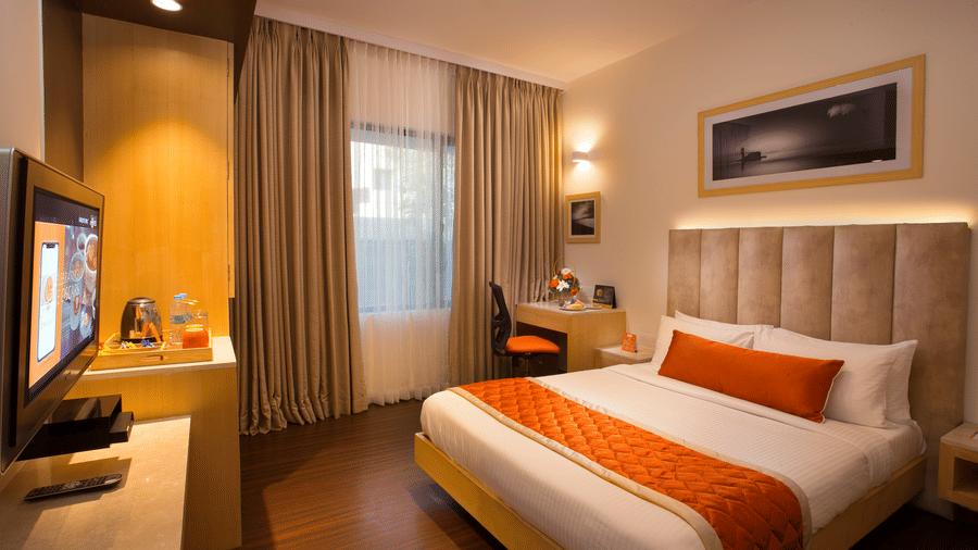 A refined Premium Room at Hotel Langford Keys by TGI with a double bed, extended cushioned headboard, bedside lighting, curtained window, and a small workspace.