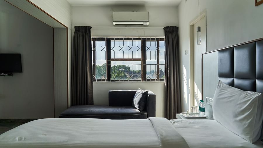 Another view of a well-appointed hotel room at Hotel Mamallaa Heritage, featuring a bed, a TV, and a window offering natural light and a view.