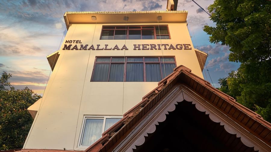 A close-up view of the upper facade of Hotel Mamallaa Heritage, clearly showing sign on the building, with a traditional roofline