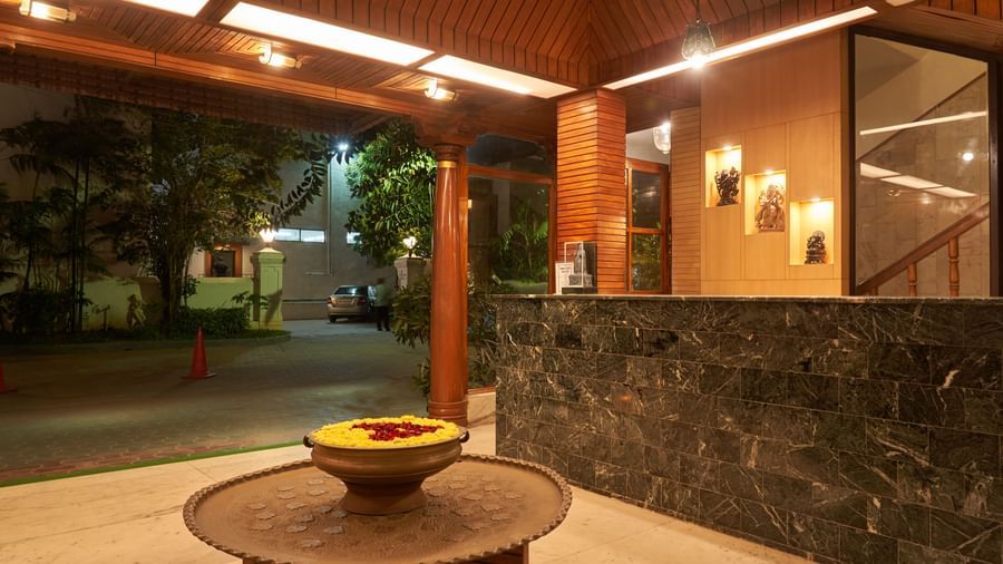 An inviting outdoor lounge or seating area at Hotel Mamallaa Heritage, with a round table and decorative bowl, under a warm light, suggesting an evening ambiance.
