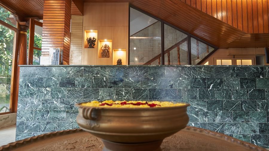 A welcoming reception or lobby area at Hotel Mamallaa Heritage, featuring modern design elements, warm lighting, and a large brass bowl as a centerpiece.