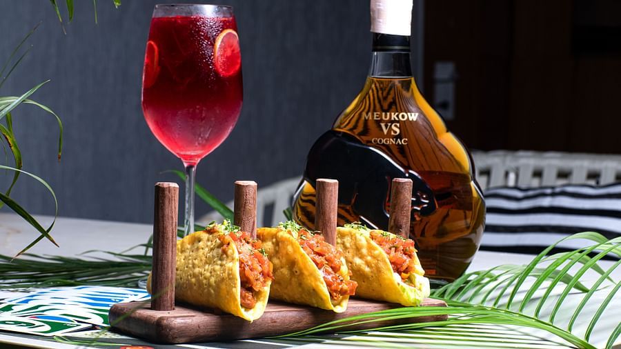 Tacos with a red cocktail and liquor bottle on a tropical table setup at Hotel Mumbai House Mindspace, Malad.
