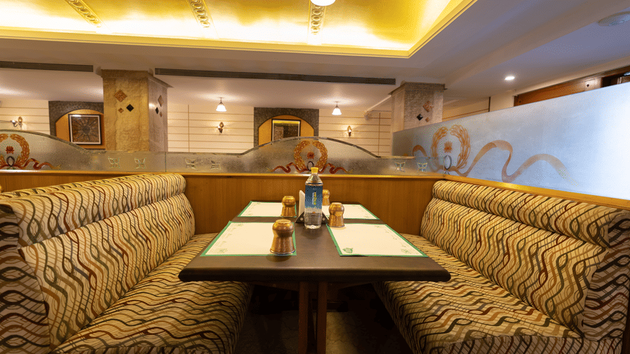 Comfortable booth seating in the restaurant at Hotel Pai Comforts, JP Nagar, featuring patterned cushioned chairs.