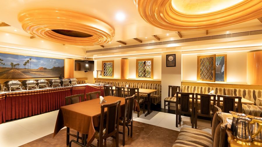 Interiors of the Royal Corner restaurant at Hotel Pai Viceroy Jayanagar featuring a buffet line, dining tables and ambient lighting