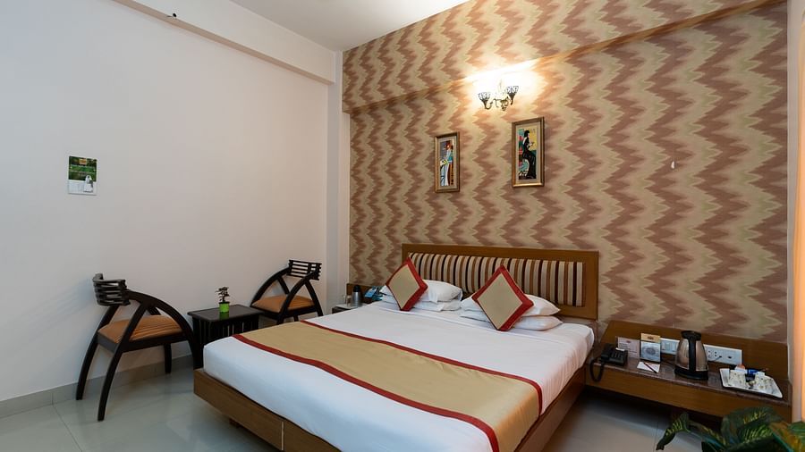 A double bed with chairs next to it inside one of the rooms - Hotel Pai Vista, KR Road