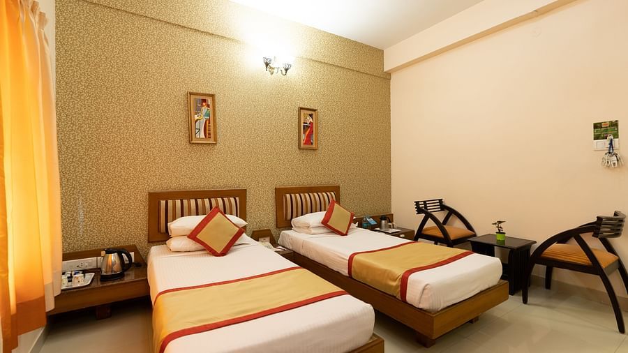 Twin bed with chairs next to it inside one of the rooms - Hotel Pai Vista, KR Road
