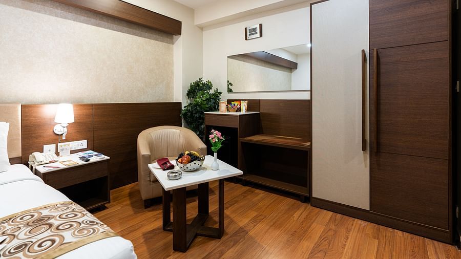 overview of a room with a single seater sofa and a table inside one of the rooms - Hotel Pai Vista, Mysore