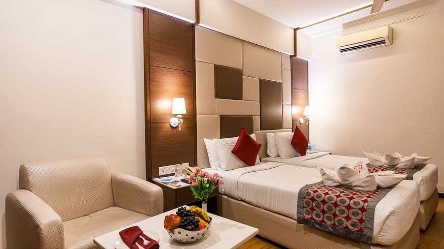 a double bed with lamps on either side and a sofa next to it inside one of the rooms - Hotel Pai Vista, Mysore