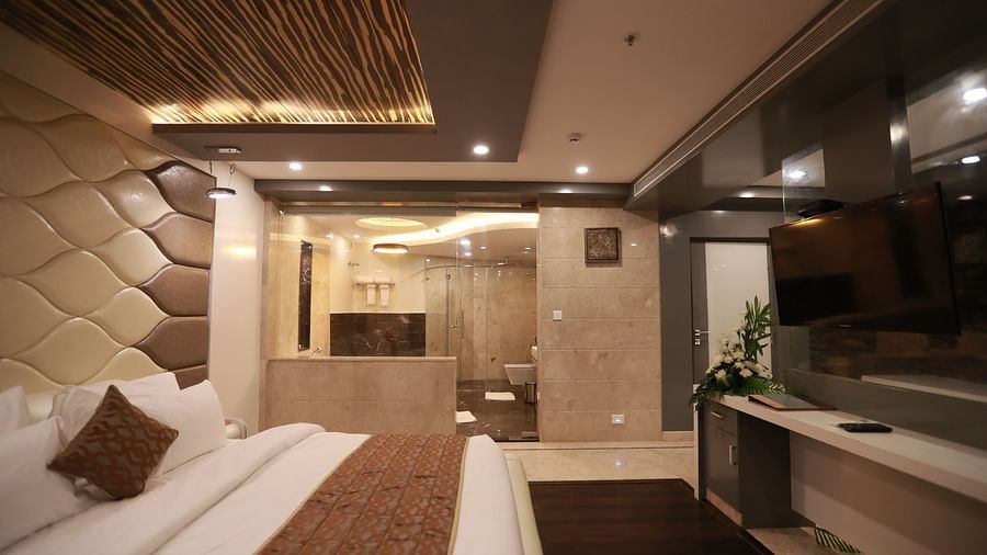 side view of a bedroom with a large bed facing the television and entrance to the washroom on the other side - Hotel Park Elanza, Chennai