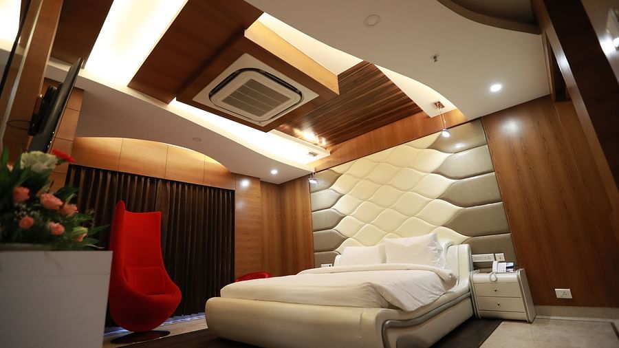 a bedroom with a large bed and a red chair with false ceiling and overhead lighting - Hotel Park Elanza, Chennai
