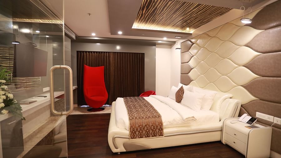 side view of a bedroom with a bed with side drawers and a red chair - Hotel Park Elanza, Chennai