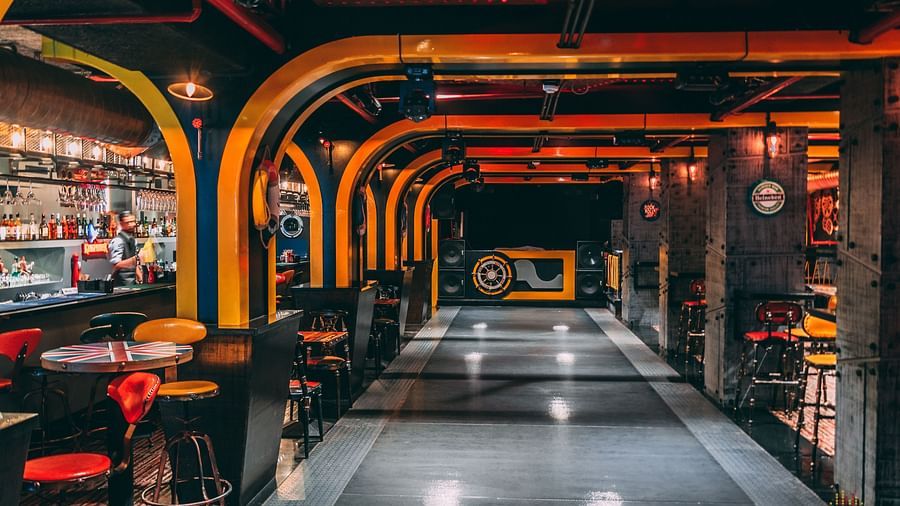 image of a bar with a bar counter on one end and tables and chairs on the other end - Hotel Park Elanza, Chennai