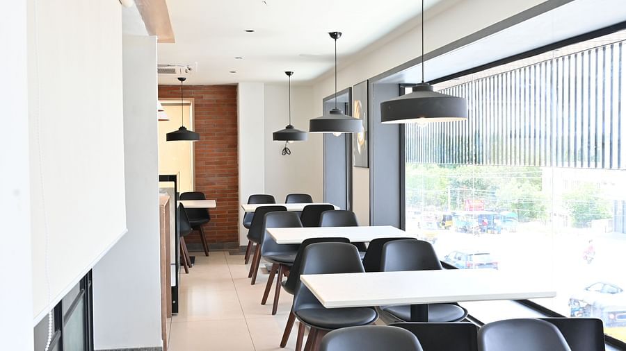 Image of coffee shop with chairs and lights hanging from the ceiling at Hotel Raai
