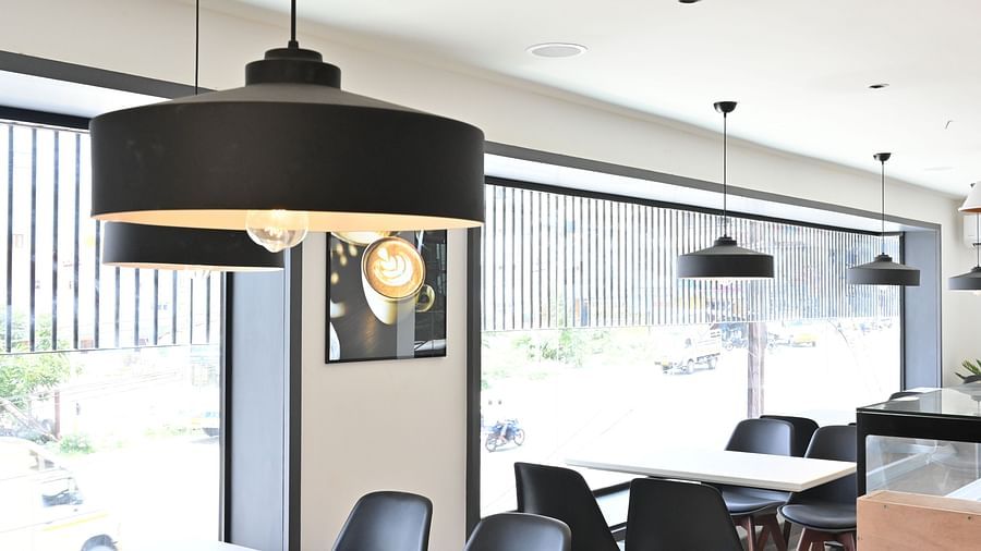 Side view of a coffee shop with chairs and lights hanging from the ceiling at Hotel Raai