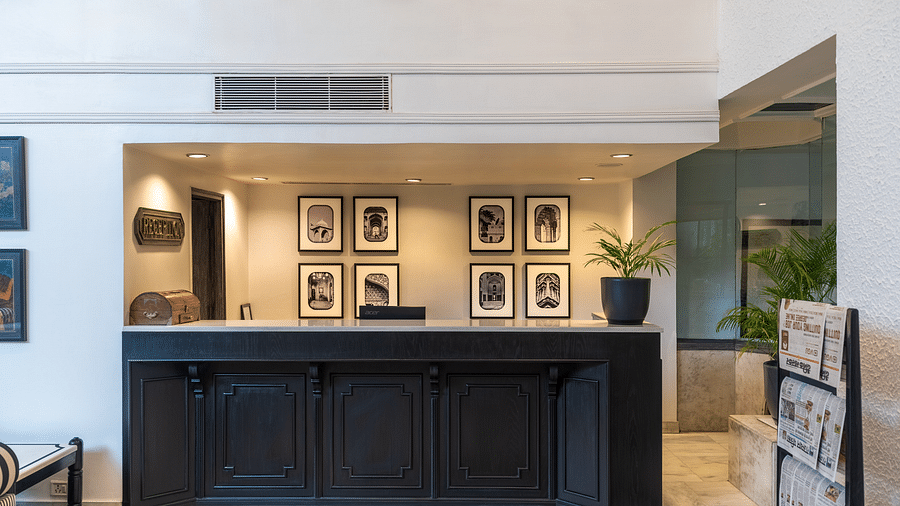 A shot of the reception featuring a front desk and pictures on the wall behind - Hotel Rajdarshan, Udaipur.