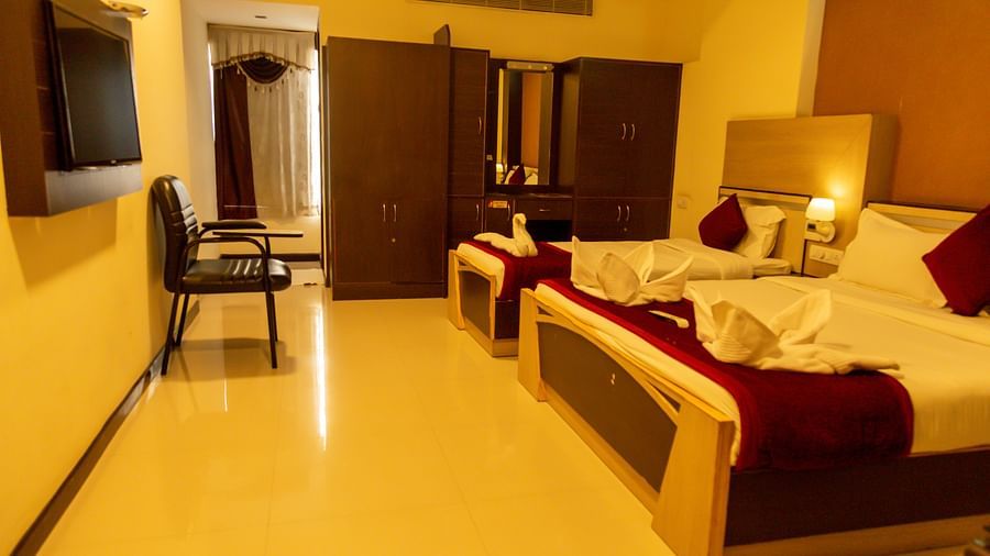 a bedroom with a large bed and a single bed facing a mounted television - Hotel Rockfort View, Trichy
