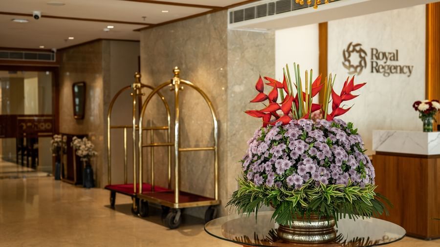 Reception area with floral arrangement and concierge desk at Hotel Royal Regency Chennai