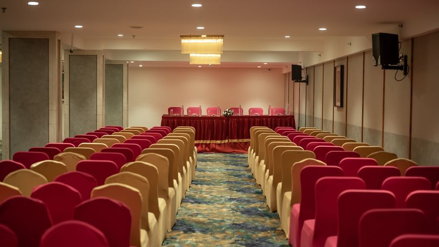 Event hall with rows of red and beige chairs arranged for a meeting at Hotel Royal Regency Chennai