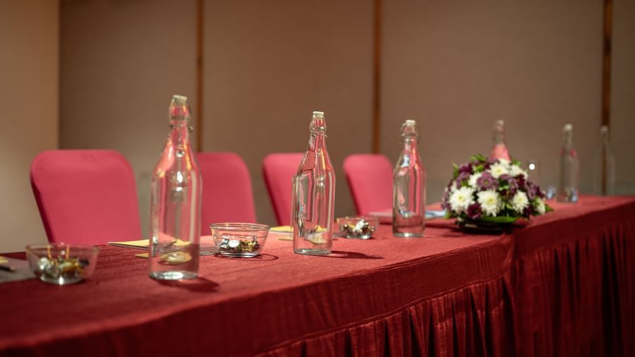 Close-up of meeting setup with glasses, and flowers at Hotel Royal Regency Chennai