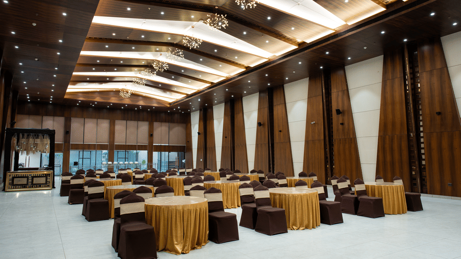 A banquet hall featuring a wooden ceiling, white flooring, and multiple round tables at Hotel Sonar Bangla, Ajodhya Hills.