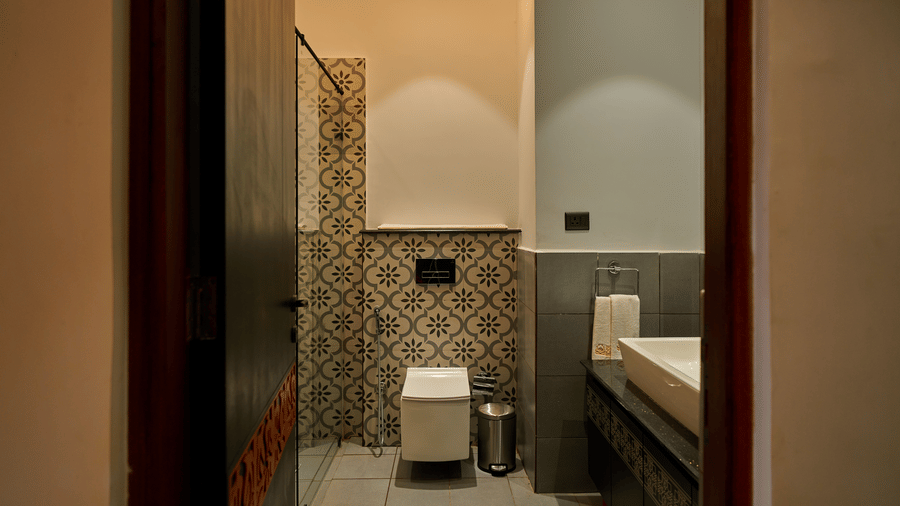 A bathroom featuring a white toilet against patterned tiles and a white basin on a counter at Hotel Sonar Bangla, Ajodhya Hills.