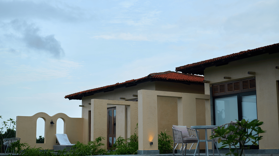 An exterior view featuring single-story buildings with terracotta roofs, a paved patio area, and a swimming pool at Hotel Sonar Bangla, Ajodhya Hills.