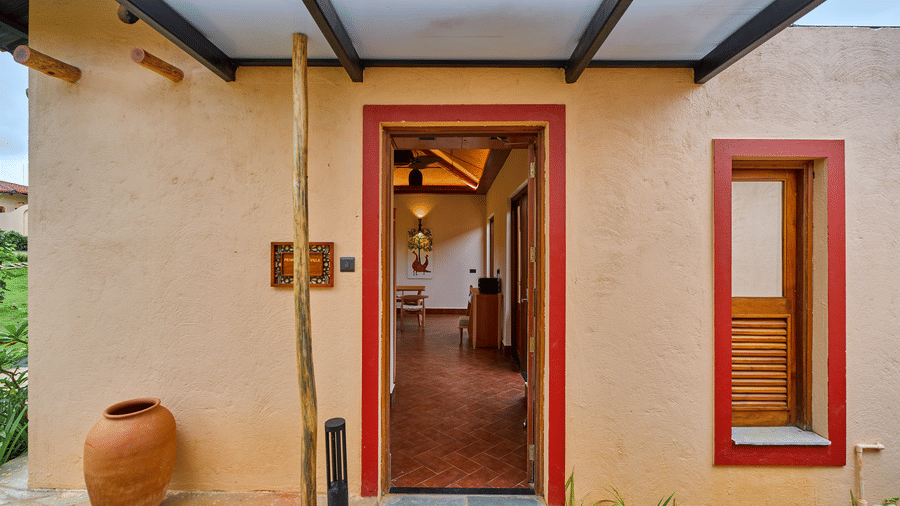 A building entrance featuring red trim around the door and a large clay pot at Hotel Sonar Bangla, Ajodhya Hills.