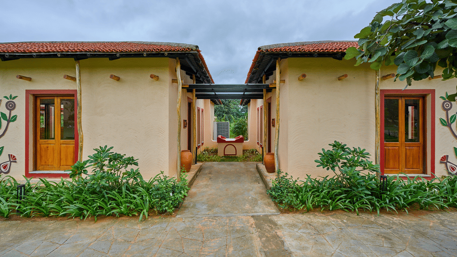 An exterior view featuring two light-coloured buildings separated by a paved pathway at Hotel Sonar Bangla, Ajodhya Hills.