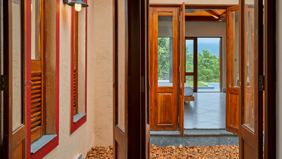 A view through open wooden doors featuring a courtyard and another room looking outside at Hotel Sonar Bangla, Ajodhya Hills.
