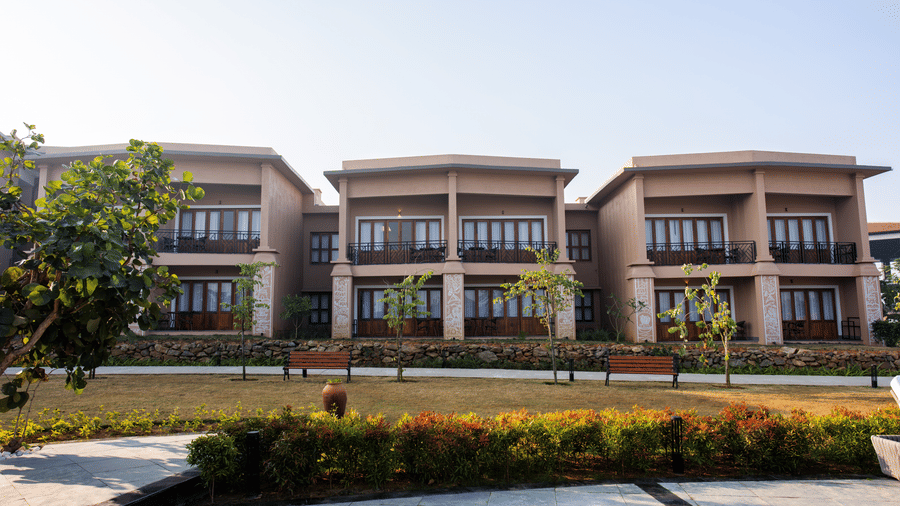 A front exterior view featuring multi-storey buildings with balconies and a paved walkway at Hotel Sonar Bangla, Ajodhya Hills.
