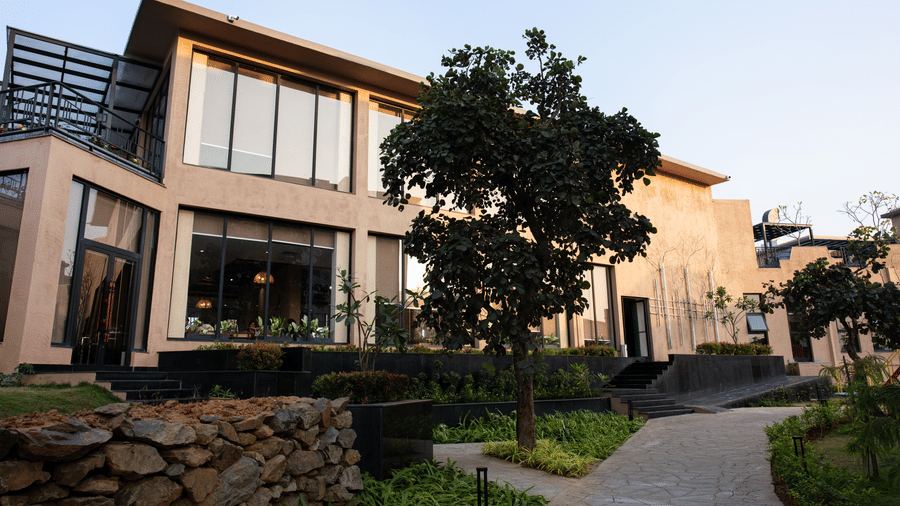 A building exterior featuring trees and a dark stone wall beside a path at Hotel Sonar Bangla, Ajodhya Hills.