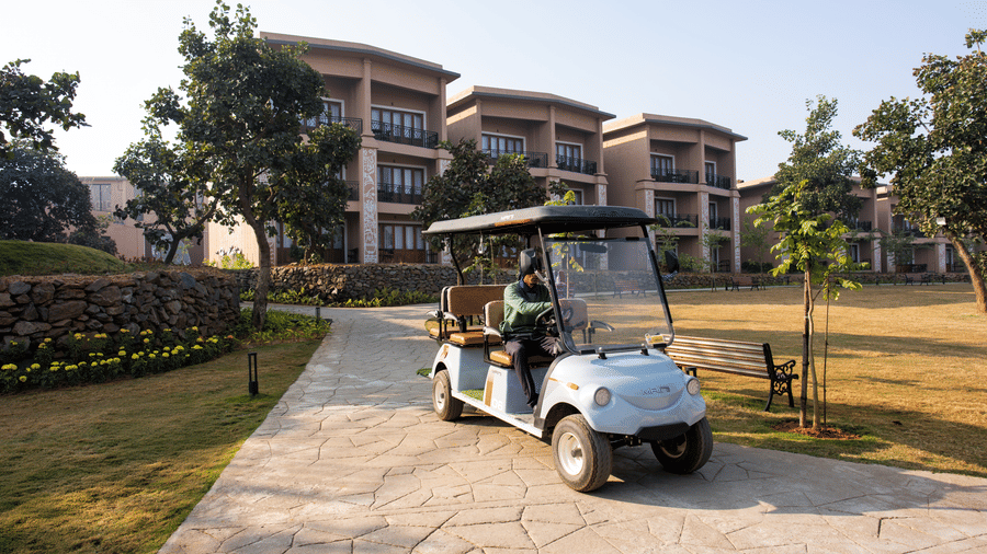 An exterior view featuring a golf cart on a paved path near multi-storey buildings and a lawn at Hotel Sonar Bangla, Ajodhya Hills.