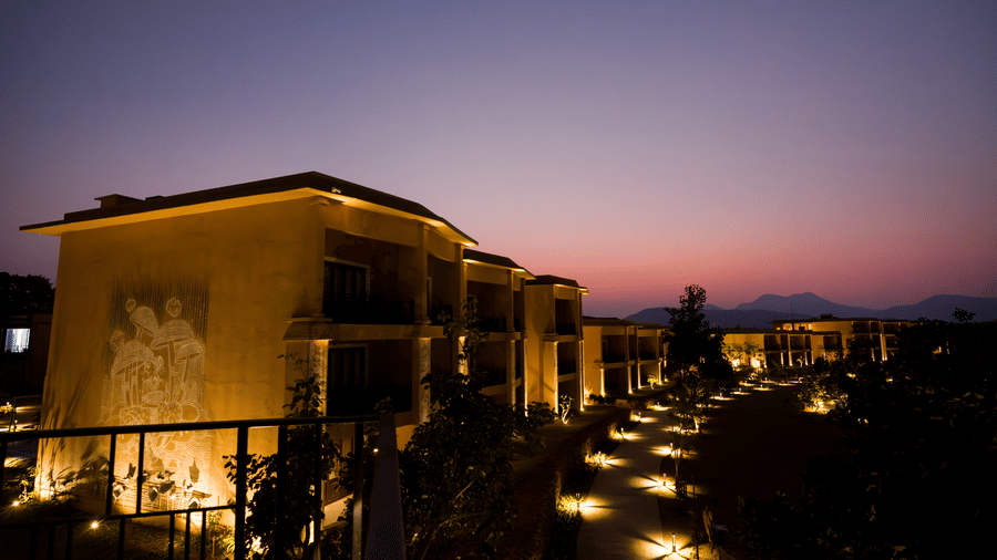 A dusk view featuring an illuminated hotel building and lit pathways under a dark sky at Hotel Sonar Bangla, Ajodhya Hills.