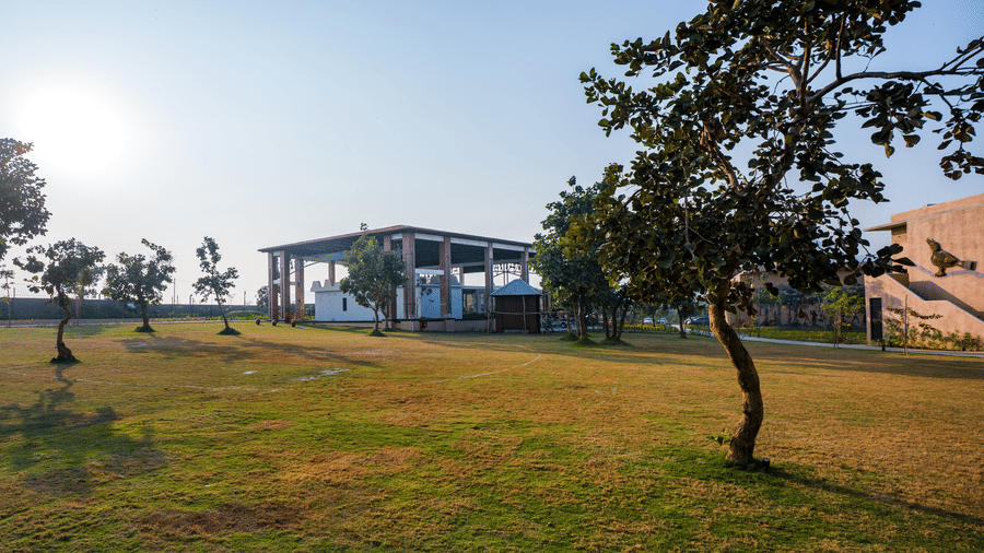 A wide outdoor view featuring a grassy lawn, several trees, and a building in the background at Hotel Sonar Bangla, Ajodhya Hills.