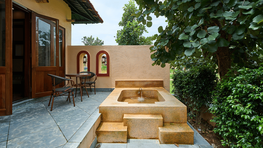 An outdoor patio featuring a stone bathtub with steps and patio seating at Hotel Sonar Bangla, Ajodhya Hills.