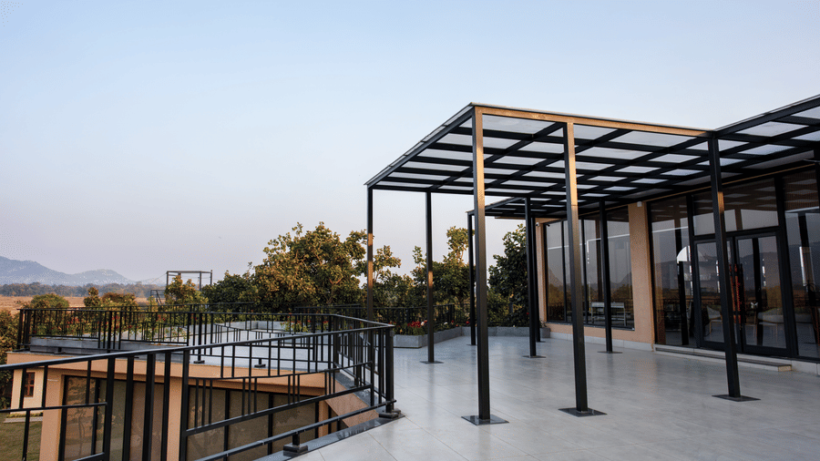 An outdoor terrace featuring a tiled floor, a black metal frame with greenery in the background at Hotel Sonar Bangla, Ajodhya Hills.