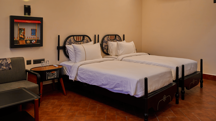 A bedroom featuring 2 single beds, a grey sofa, and terracotta flooring at Hotel Sonar Bangla, Ajodhya Hills.